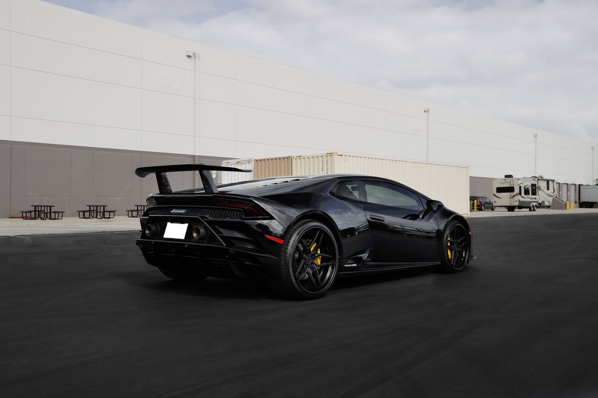 Black Lamborghini Huracán parked outside an industrial warehouse